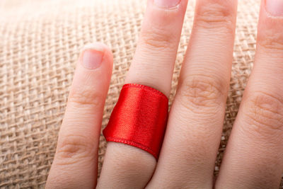 Cropped hand with red ribbon on burlap