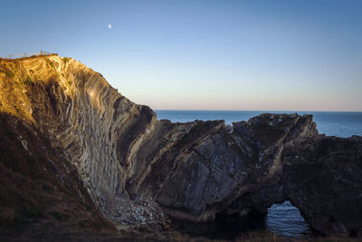 Rock formations by sea against sky