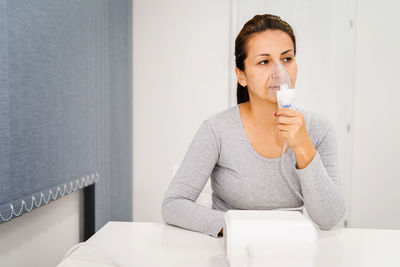 Mature woman using inhaler at hospital