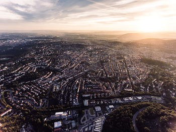 Aerial view of cityscape against cloudy sky during sunset