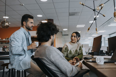 Businesswoman discussing strategy with male colleagues at corporate office