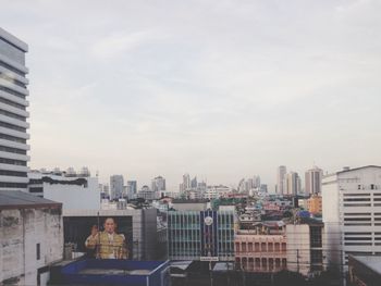 Man waving hand while standing in city against sky