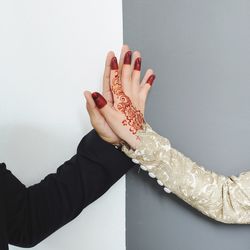 Cropped image of couple holding hands against wall