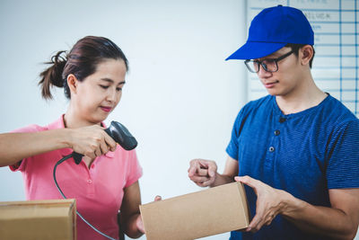 Businesswoman scanning while colleague holding box