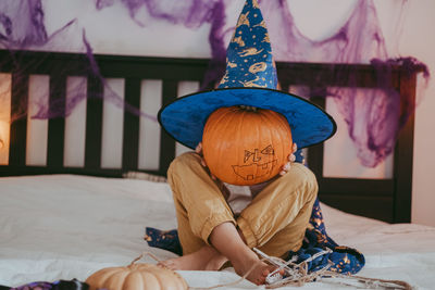 Cute little caucasian boy in a halloween costume with big orange pumpkin jack-o-lantern.