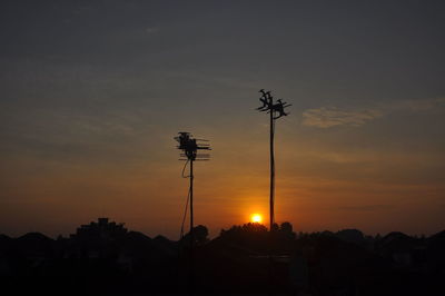 Low angle view of silhouette telephone pole against sky during sunrise