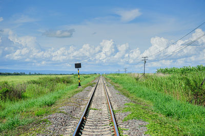 Railroad tracks on field against sky