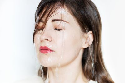 Close-up portrait of young woman against white background