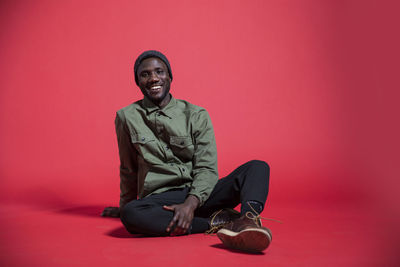 Portrait of young man looking away against red background