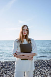 Portrait of young woman standing against sea