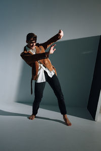 Full length of young man dancing against white background