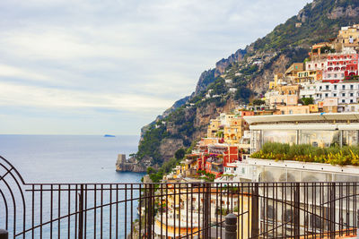 Scenic view of sea by mountain against sky