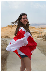 Portrait of smiling young woman standing with canadian flag