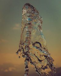Close-up of water splashing against sky during sunset