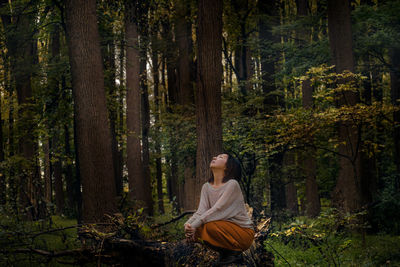 Woman looking up when sitting in forest