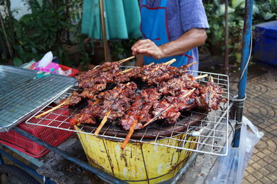 Midsection of man grilling meat on barbecue