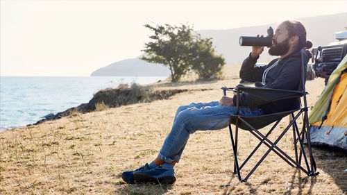 Full length of man photographing while sitting on beach