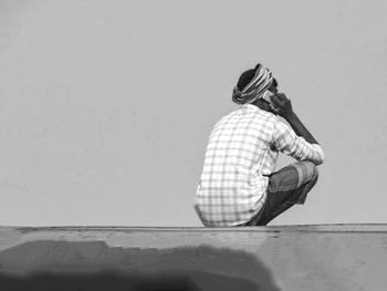 Side view of a man sitting against white background