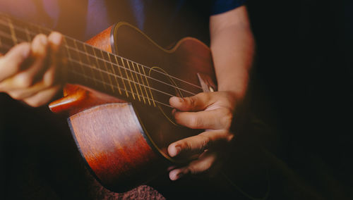 Midsection of man playing guitar