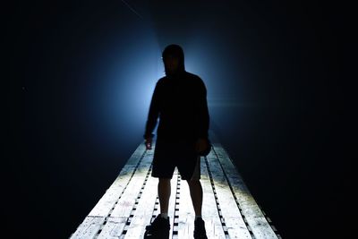Man standing on footbridge at night