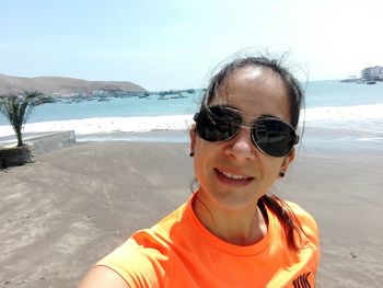 Portrait of smiling young woman in sunglasses against sea