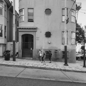 Rear view of people walking on street amidst buildings