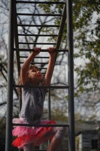 Girl climbing on monkey bars against sky