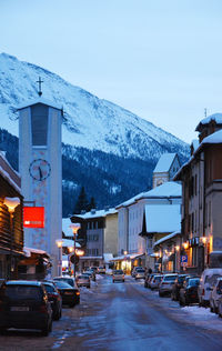 Cars on street amidst buildings in city during winter