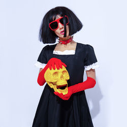 Demonic gothic stylish brunette lady in red gloves holding gold skull. role-playing games, halloween