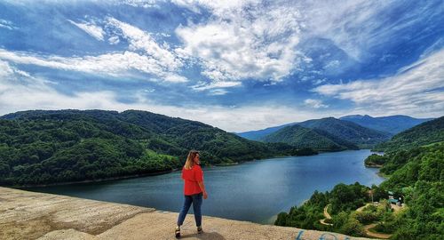 Rear view of woman standing on mountain against sky