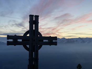 Silhouette cross against sky during sunset