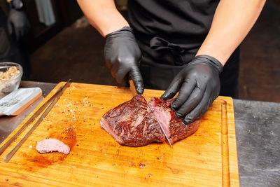 Midsection of chef cutting meat