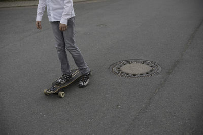 Low section of man skateboarding on road