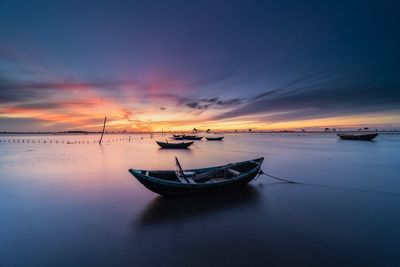 Boat moored on sea against sky during sunset