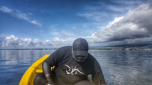 Man sitting by sea against sky