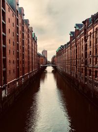 Canal amidst buildings in city against sky