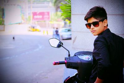 Boy in sunglasses sitting on motor scooter