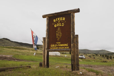 Information sign on field against sky