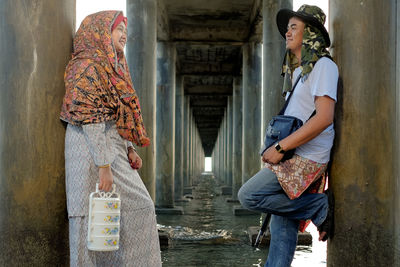 Smiling friends leaning on architectural column