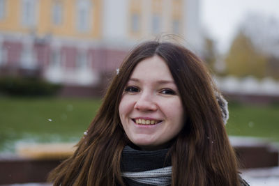 Portrait of smiling woman with long hair standing at park during winter