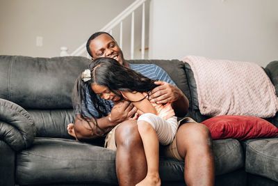 Father and kids at home playing on couch, african american or black father with his children