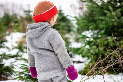 Rear view of 3 year old in winter looking for a christmas tree