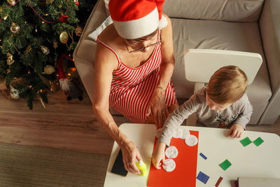 High angle view of grandmother and grandson making craft product on table