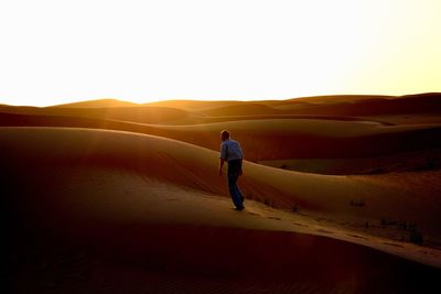 Rear view of man walking on desert