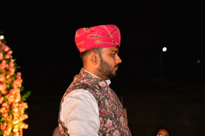 Side view of young man standing against sky at night