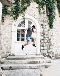 Full length of young man jumping against door