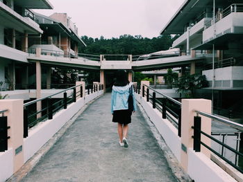 Rear view of woman walking on bridge in city