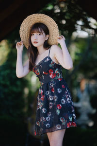 Portrait of young woman wearing hat standing outdoors