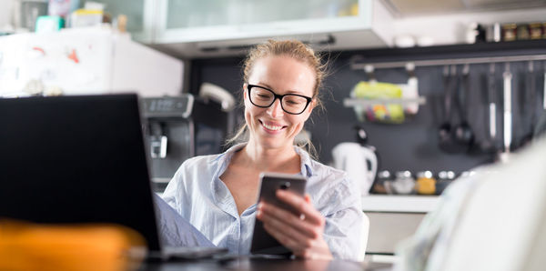 Beautiful businesswoman using smart phone while working at home