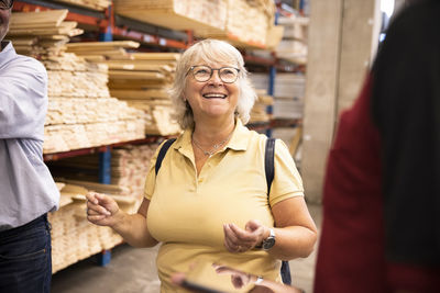 Happy senior woman wearing eyeglasses looking at saleswoman in hardware store